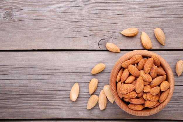 Wooden bowl of almonds on grey wooden 