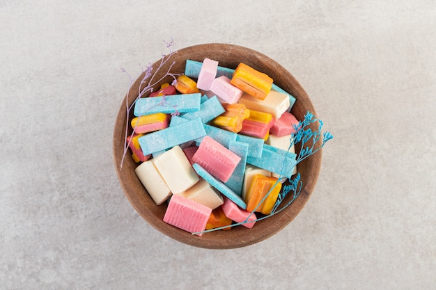 Wooden bowl of colorful aroma gums on stone table.