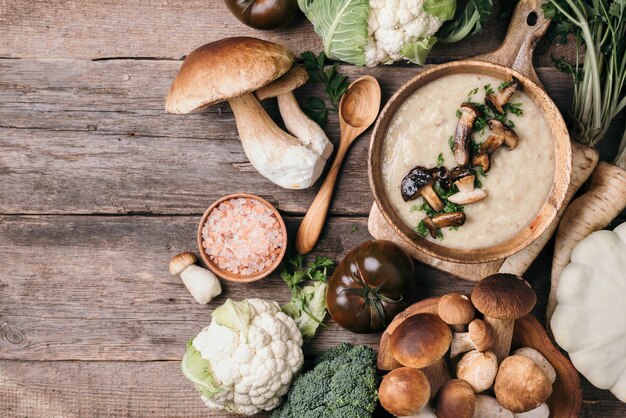 Foto ciotola di legno di zuppa di funghi crema con funghi fritti verdure spezie crudo boletus edulis fungo su sfondo di legno vista dall'alto spazio di copia concetto di raccolto autunnale