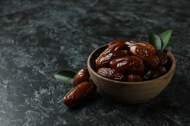 Wooden bowl of dates on black smokey