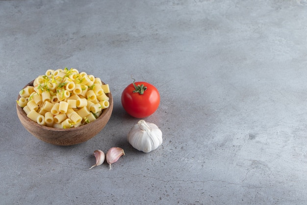 Wooden bowl of delicious boiled pasta on stone background. 