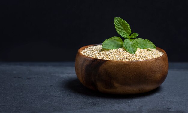 Wooden bowl filled with quinoa on black