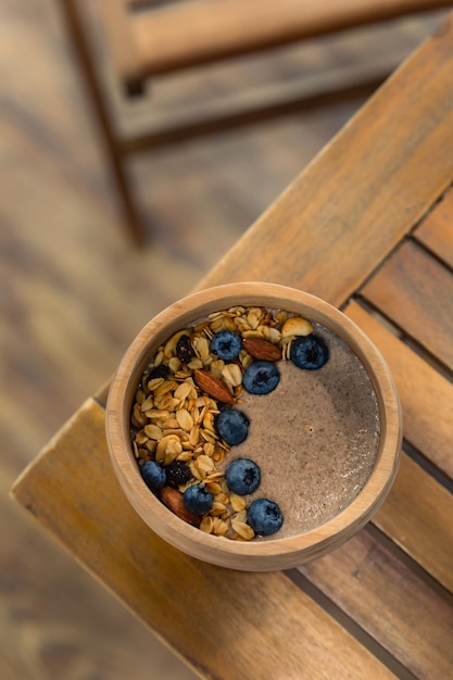 Ciotola di legno di semi di lino o porridge di lino con mirtilli, mandorle e muesli sana colazione vegana