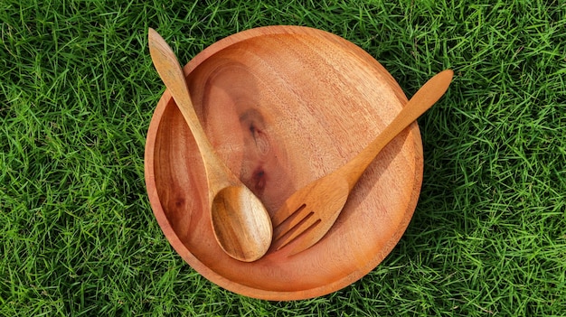 Wooden bowl and fork on the grass