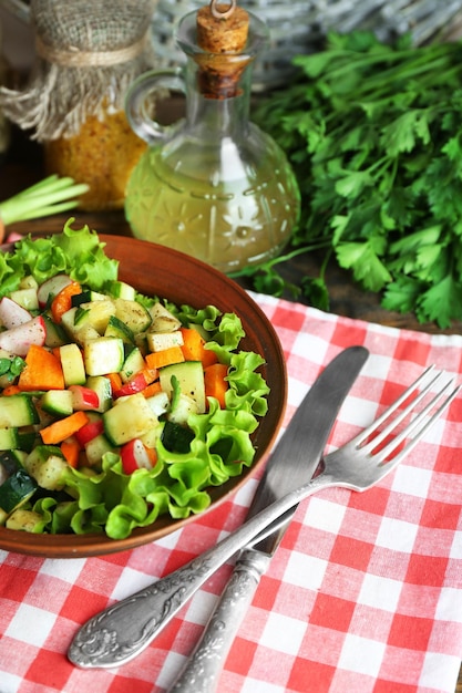 Wooden bowl of fresh vegetable salad on napkin closeup