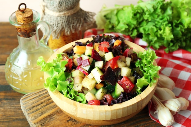 Wooden bowl of fresh vegetable salad on table closeup