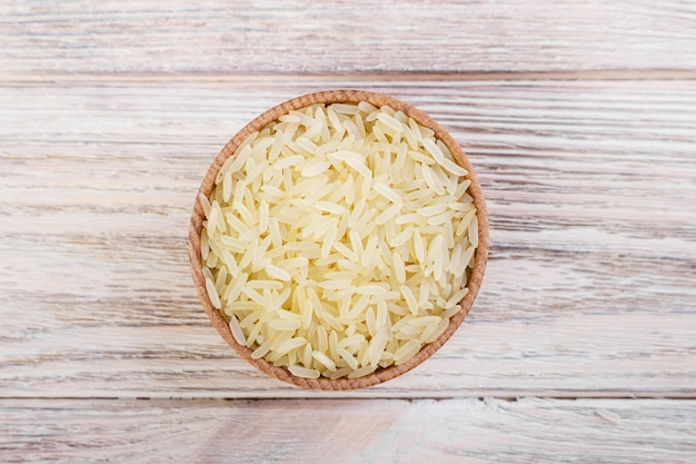 Wooden bowl full of basmati rice, top view.