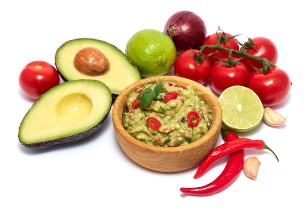 Wooden bowl of guacamole dip sauce and ingredients isolated on white background