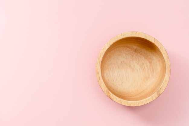 Wooden bowl on pink background for utensil and kitchenware concept