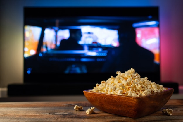 Wooden bowl of popcorn and remote control