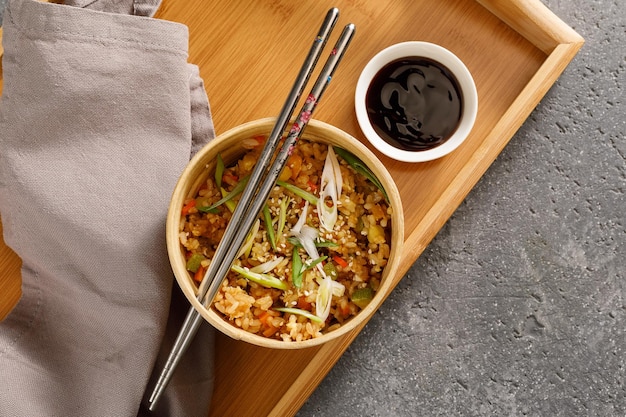 Wooden bowl of rice with vegetables served with chopsticks Traditional asian food