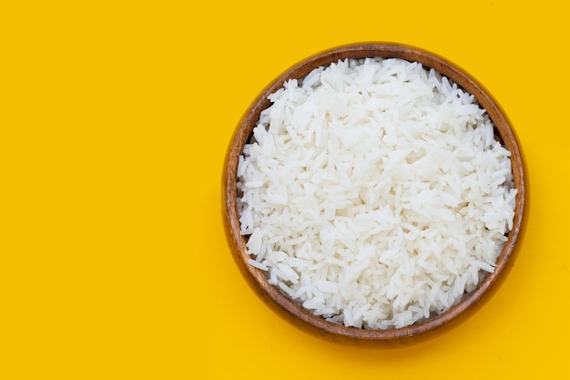 Wooden bowl of rice on yellow background