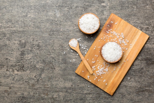 A wooden bowl of salt crystals on a wooden background Salt in rustic bowls top view with copy space