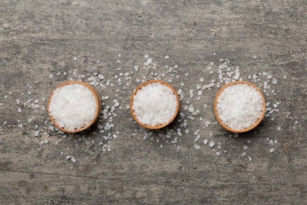 A wooden bowl of salt crystals on a wooden background Salt in rustic bowls top view with copy space