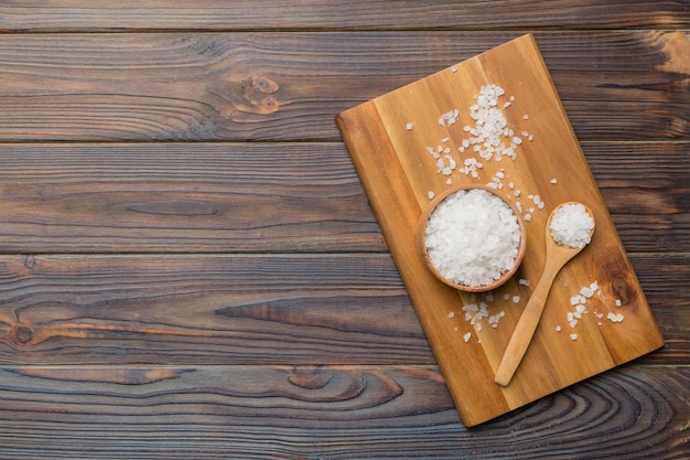 Photo a wooden bowl of salt crystals on a wooden background salt in rustic bowls top view with copy space