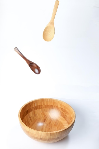 Wooden bowl spoon utensils on white background elevated flying floating