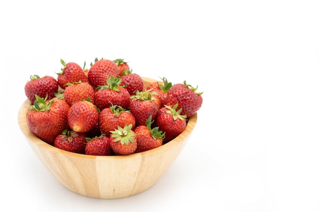 A wooden bowl of strawberries on a white background