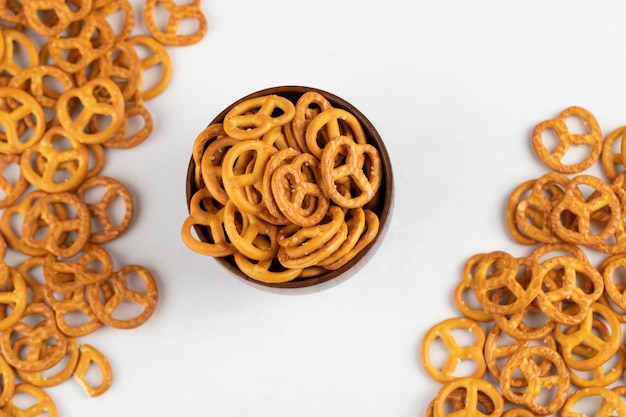 Wooden bowl of tasty crunchy pretzels on white surface.