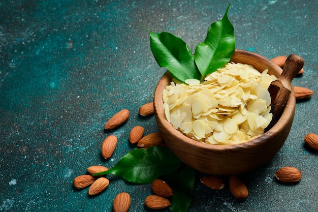 A wooden bowl with almond slices Almond chips On a dark turquoise background Copy space