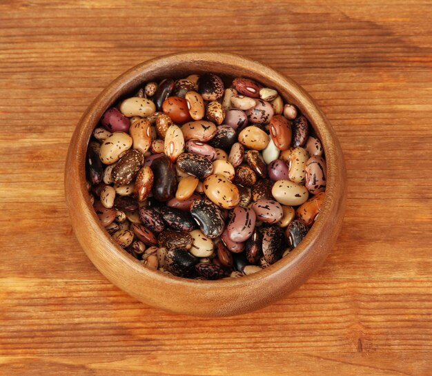 Wooden bowl with beans on wooden background