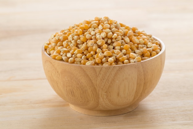 Wooden bowl with corn seeds on wooden table