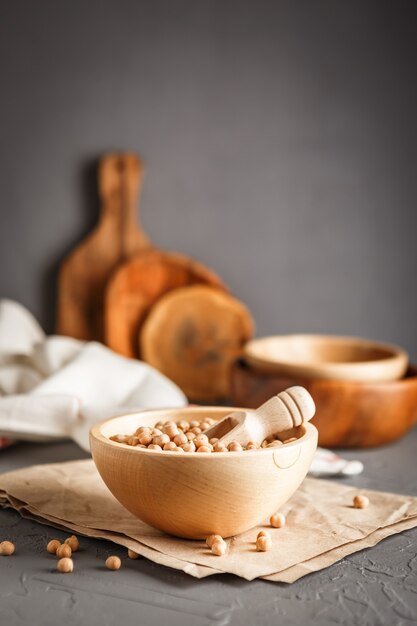 Wooden bowl with dry raw organic chickpeas on gray concrete