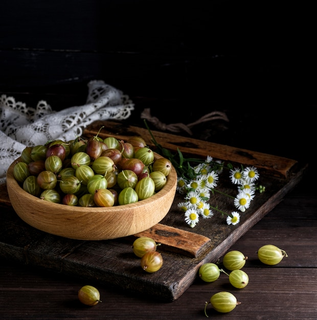 Wooden bowl with green gooseberries 