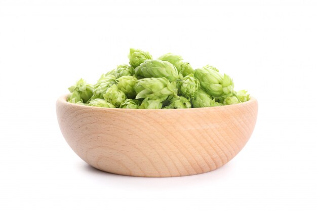 Wooden bowl with hop cones isolated on white