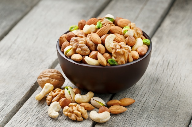 Wooden bowl with mixed nuts on a wooden gray surface