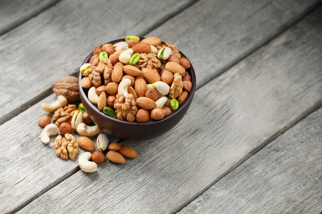 Wooden bowl with mixed nuts on a wooden gray surface