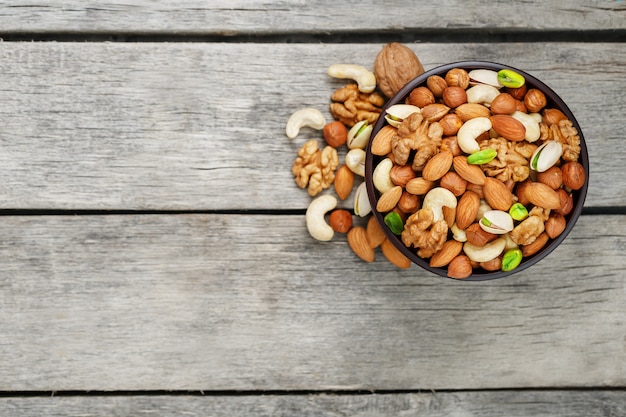 Wooden bowl with mixed nuts on a wooden gray . Walnut, pistachios, almonds, hazelnuts and cashews, walnut.