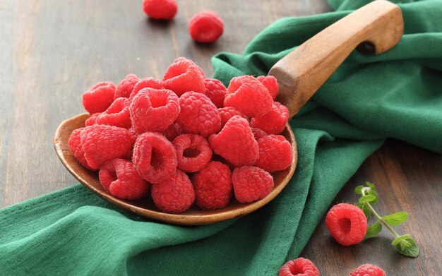 a wooden bowl with raspberries on it and a wooden spoon