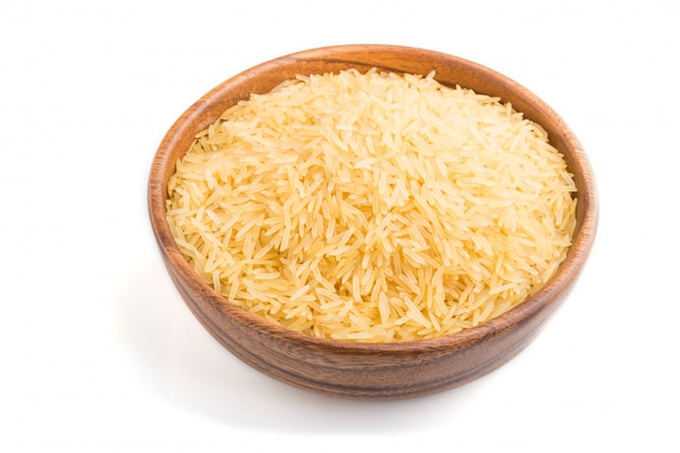 Wooden bowl with raw golden rice isolated on white background. Side view.