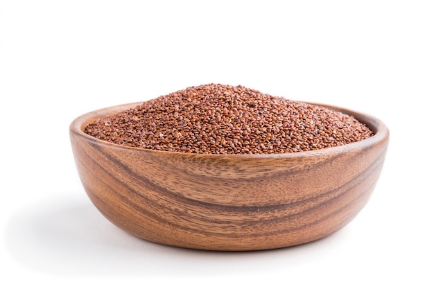 Wooden bowl with raw red quinoa seeds isolated on white surface