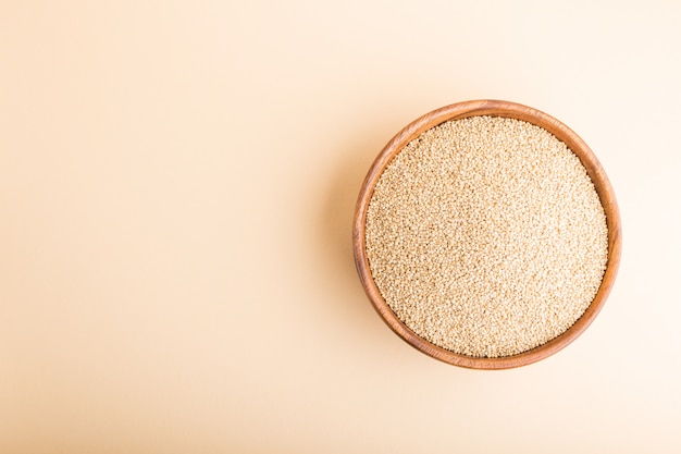 Photo wooden bowl with raw white quinoa seeds