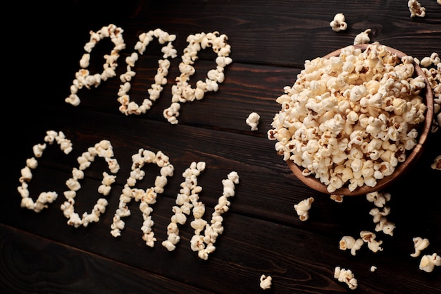 Ciotola di legno con popcorn salato su un tavolo di legno. sfondo scuro messa a fuoco selettiva. disteso. u: ugryumov igor