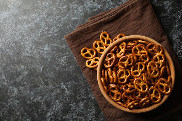 Wooden bowl with tasty cracker pretzels on napkin