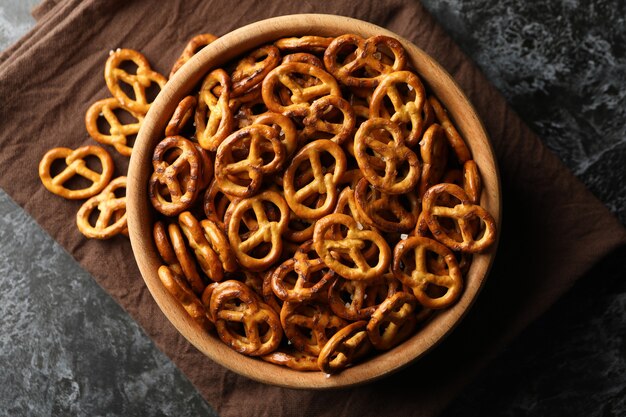 Wooden bowl with tasty cracker pretzels on napkin