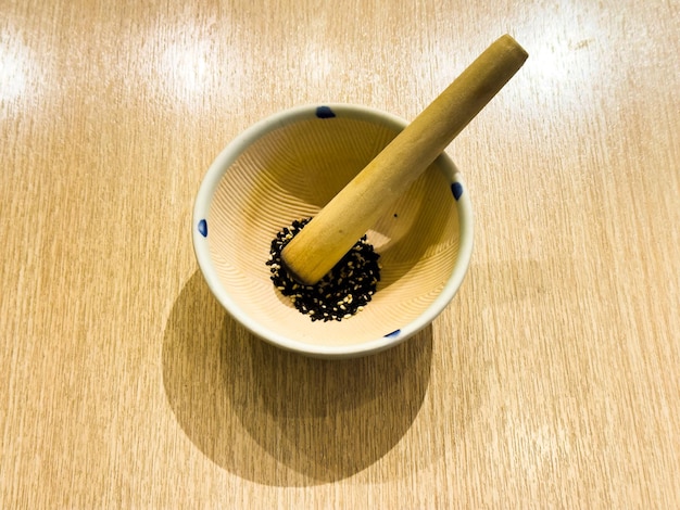 A wooden bowl with a wooden handle and a wooden spoon with black seeds in it.