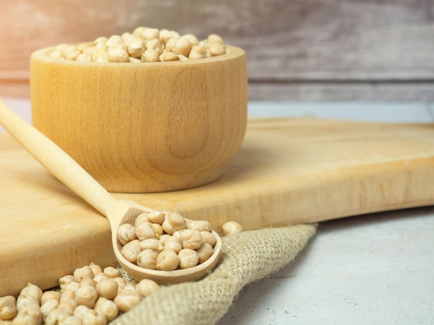 Wooden bowl and wooden spoon full of chickpeas on a light concrete background. close-up