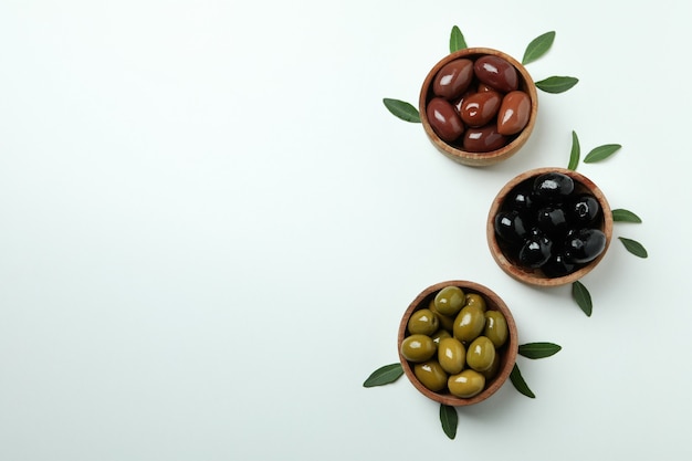 Wooden bowls of olives and leaves on white isolated background