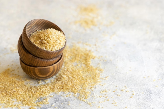 Wooden bowls with Dry uncooked bulgur wheat grain close up copy space Healthy food