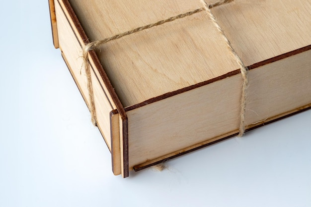 Wooden box drawn by a rope on a white background rustic style packaging made of wood and waxed cord ...