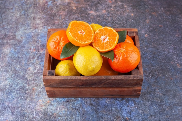 Scatola di legno piena di frutta fresca su sfondo marmo.