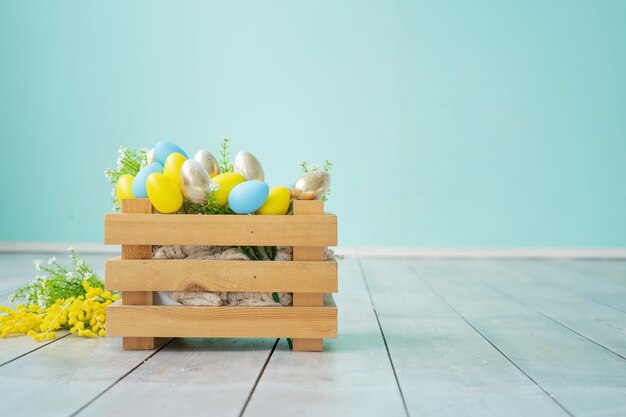 Wooden box with blue, yellow and gold Easter eggs against a blue wall