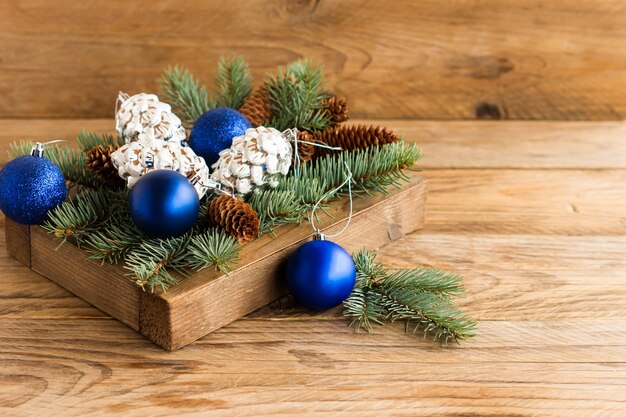 Wooden box with christmas blue balls and silver cones on the\
village table. the concept of meeting the new year and cozy\
christmas.