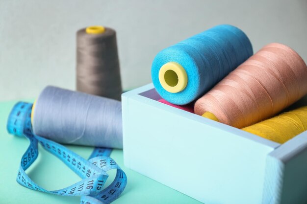 Wooden box with color sewing threads on table