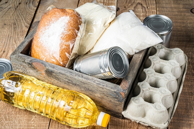 Wooden box with Donation food, quarantine help concept. Oil, canned food, pasta, bread, sugar, egg