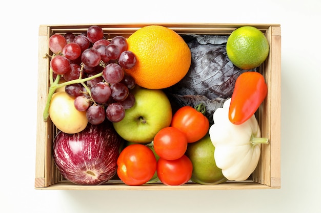 Wooden box with vegetables and fruits on white background