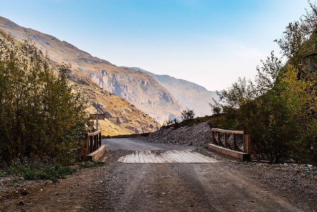 Wooden bridge over ravine on mountain road. Russia, Altai, Chulyshman Valley